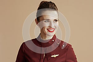 happy elegant female air hostess on beige looking at copy space