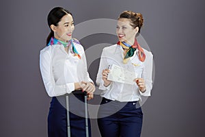 happy elegant female air hostesses against gray background