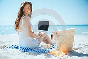 happy elegant female on ocean coast with straw bag