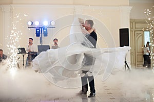 happy elegant married couple performing first dance in a restaurant, celebrating wedding