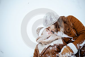 happy elegant mother and daughter laying in snow