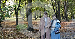 Happy, elegant, retired family couple walking and having pleasant talk in autumn