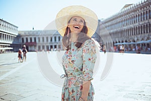 Happy elegant woman in floral dress having excursion photo