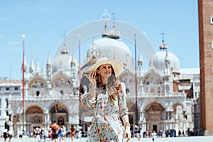 Happy elegant tourist woman in floral dress talking on phone