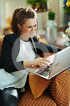 Happy elegant woman doing research while sitting on sofa