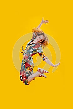 Happy elegant woman jumping in the air over yellow taking artistic form