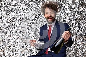 Happy elegant young man holding wine bottle and glasses and smiling