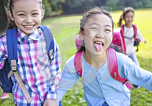 Happy elementary school kids running on the grass