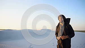 Happy Emirate man walks on outskirts of desert with smile on face on clear summer evening