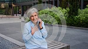 Happy emotional Caucasian old female businesswoman senior excited woman talking mobile phone in city smartphone call
