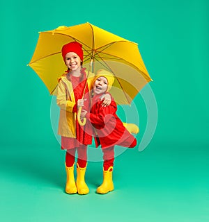 happy emotional cheerful children friends laughing  with yellow umbrella   on colored green background