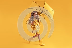 Happy emotional girl laughing with umbrella on colored yellow background. Autumn, spring season