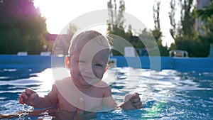 Happy emotions of child, cheerful smiling infant in backlight having fun in pool