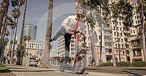 Happy employer in formalwear have fun riding escooter on sidewalk, recreation photo