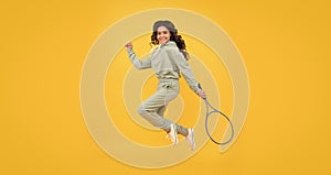 happy energetic child jump in sportswear with squash racquet on yellow background, sport success