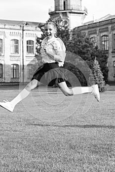 Happy energetic child in uniform with school bag jumping for joy, back to school