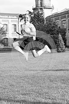 Happy energetic girl child in uniform back to school jumping for joy, September 1