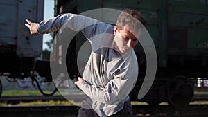 Happy energetic guy dancing on background passing trains. Emotions joy man