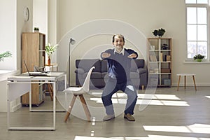 Happy energetic mature businessman doing squats during working day in his home office