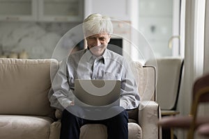 Happy engaged older laptop user man working at home