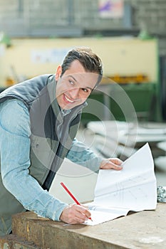 happy engineer with plan looking at blueprint