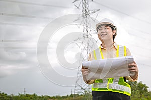 Happy engineer woman happy smiling with high voltages electricity transmission pole building project on background