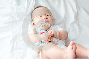 Happy and enjoy Portrait of a newborn Asian baby boy on the bed ,a dummy in his mouth, Charming