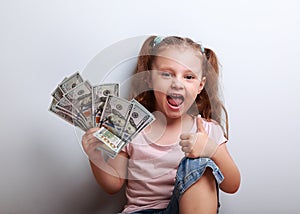 Happy enjoying kid girl holding money and showing thumb up sign