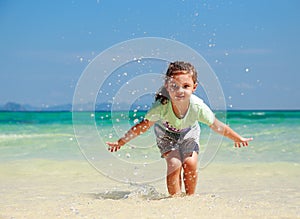 Happy enjoying kid girl playing and splashing with water on blue