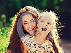 Happy enjoying mother hugging her relaxing smiling kid girl on bright summer green trees background. Closeup portrait