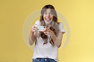 Happy enthusiastic excited cute playful girl winning awesome smartphone game thrilled playing stare camera surprised