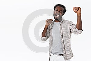 Happy, enthusiastic good-looking african-american bearded man do lucky dance, celebrating success, raising hands up in