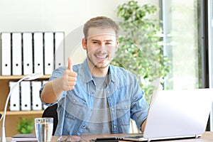 Happy entrepreneur gesturing thumbs up at office