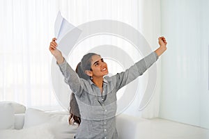 Happy entrepreneur woman reading good news in a letter on sofa