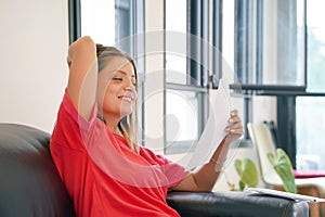 Happy entrepreneur woman reading good news in a letter on sofa