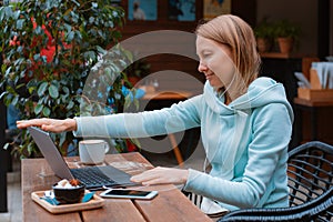 Happy entrepreneur working with a phone and laptop in a coffee shop in the street