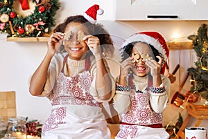 Happy ethnic children on Christmas eve,   girl and boy covers eyes with cookies gingerbreads that they baked and laughs  in cozy