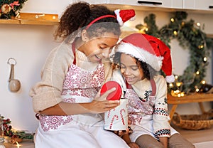 Happy ethnic children on Christmas eve,   girl and boy eat cookies that they baked together in cozy kitchen at home