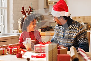 Happy ethnic family father and child pack Christmas gifts