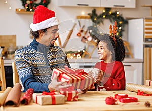 Happy ethnic family father and child pack Christmas gifts