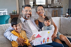 Happy ethnic family showing painting with new home