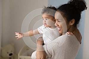 Happy ethnic mom dream of future with little baby toddler