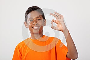 Happy ethnic school boy 11 makes okay hand sign