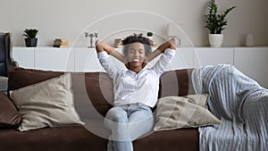 Happy ethnic woman relax on sofa taking nap