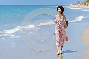 Happy ethnic woman on sandy seashore