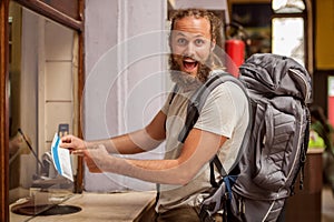 Happy and euphoric backpacker male tourist shows ticket for his