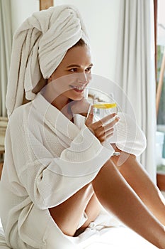 Happy european girl drink lemonade in bathrobe