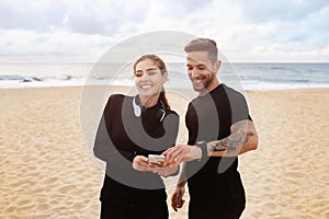 Happy european man and woman preparing for workout, chatting before morning run on the beach of ocean