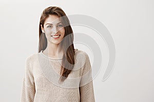 Happy that everything is okay. Portrait of charming friendly caucasian girl in casual sweater smiling cheerfully while