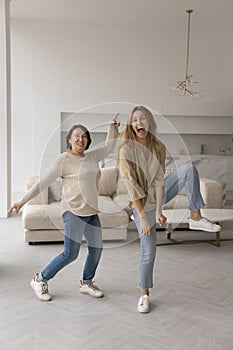 Happy excited adult daughter and joyful active senior parents dancing